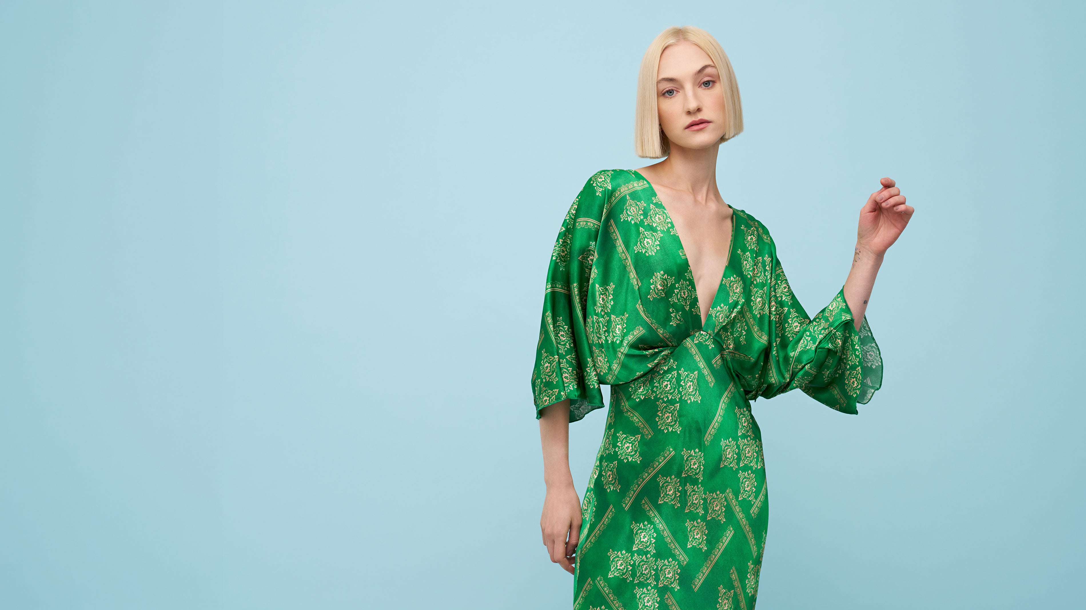 Woman wearing a green patterned dress against a light blue background